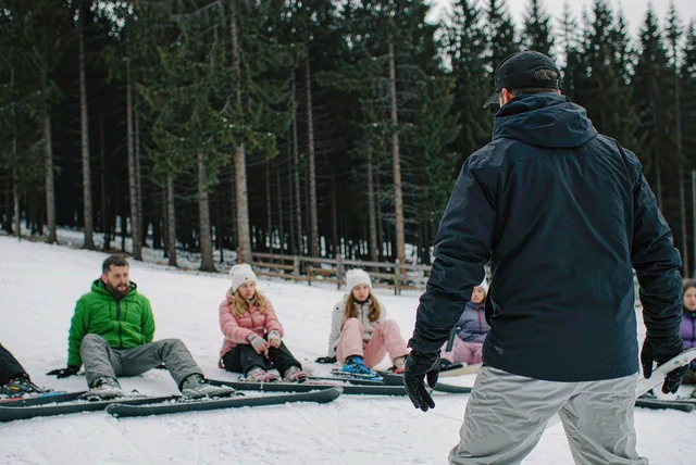 An instructor teaching a small group of beginners on a nursery slope