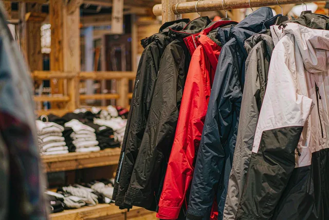 Snowboard jackets hanging in a row on a rack in a resort shop