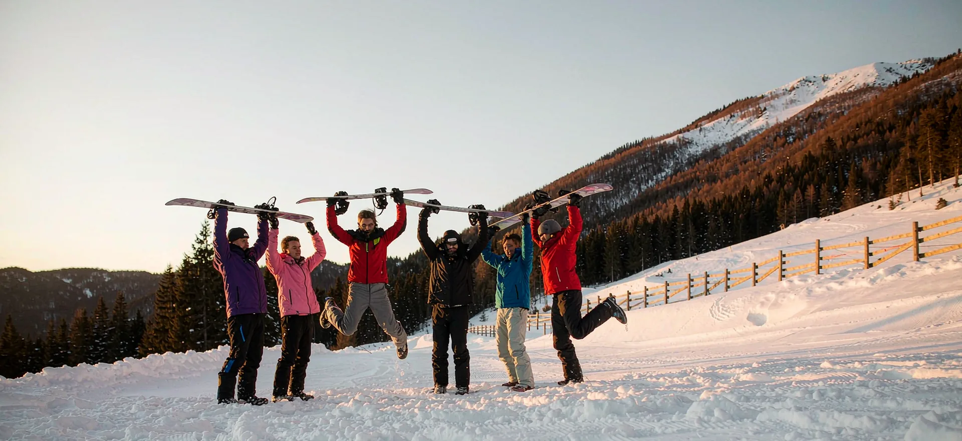 A group of friends cheering in deep powder on a bright winter day