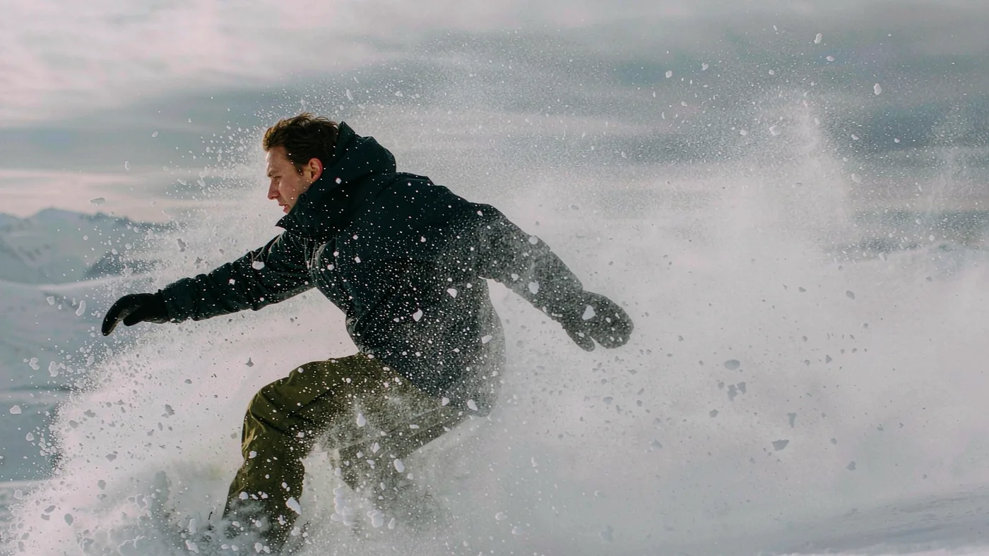 A rider blasting through deep untracked snow with snow spraying over the nose of the board