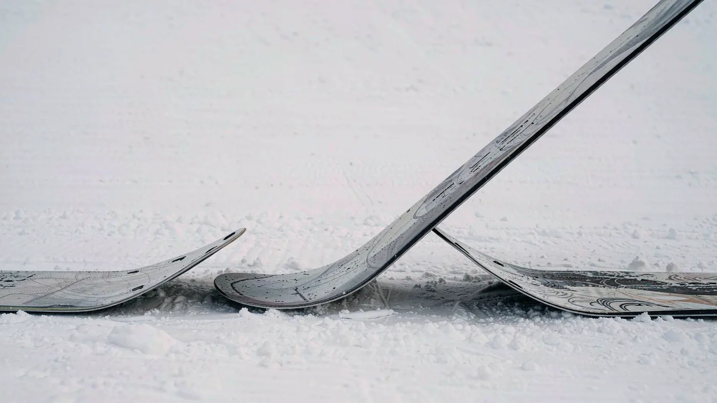 A snowboard lying on a workbench seen from the side showing its profile curve