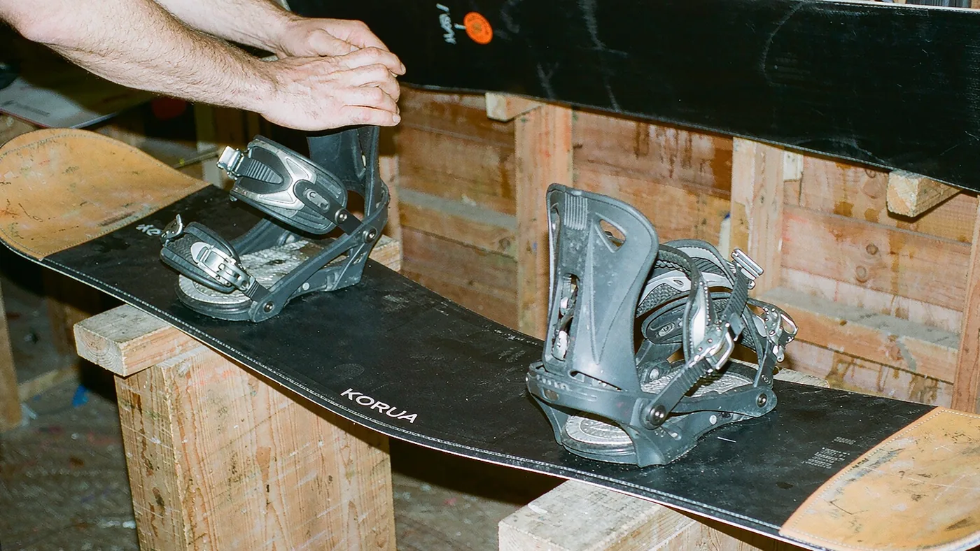 Hands pressing the middle of a snowboard to show how the board flexes under load