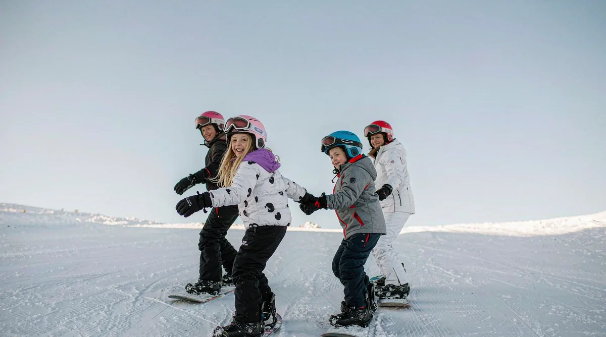 A family snowboarding together down a wide, easy slope